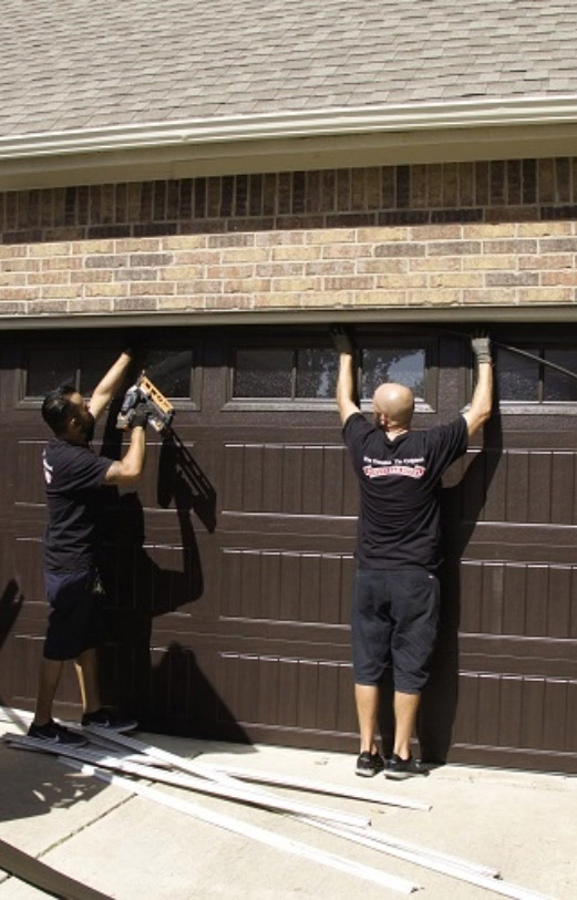 Two men repair a garage door