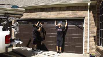 Two Overhead Doors staff members repair a garage door
